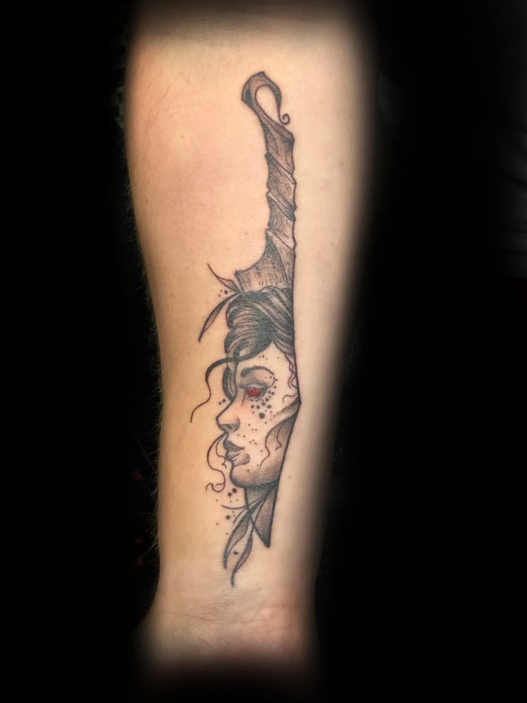 Black and grey woman and snake tattoo on the forearm