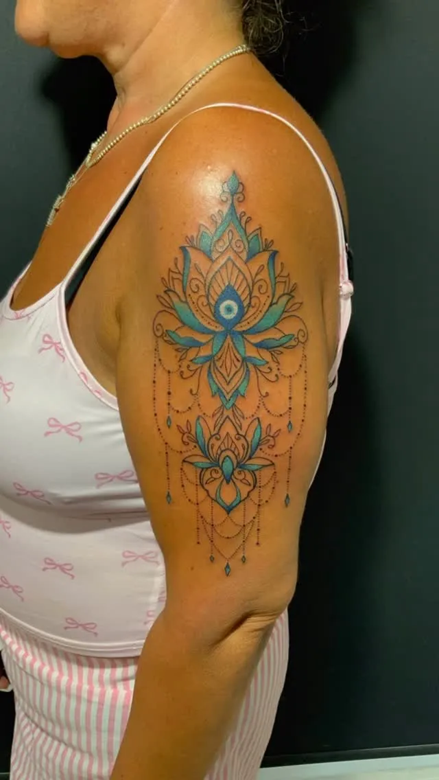 Ornamental mandala shoulder tattoo with teal accents
